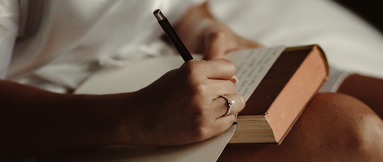A hand writing vows in a notebook