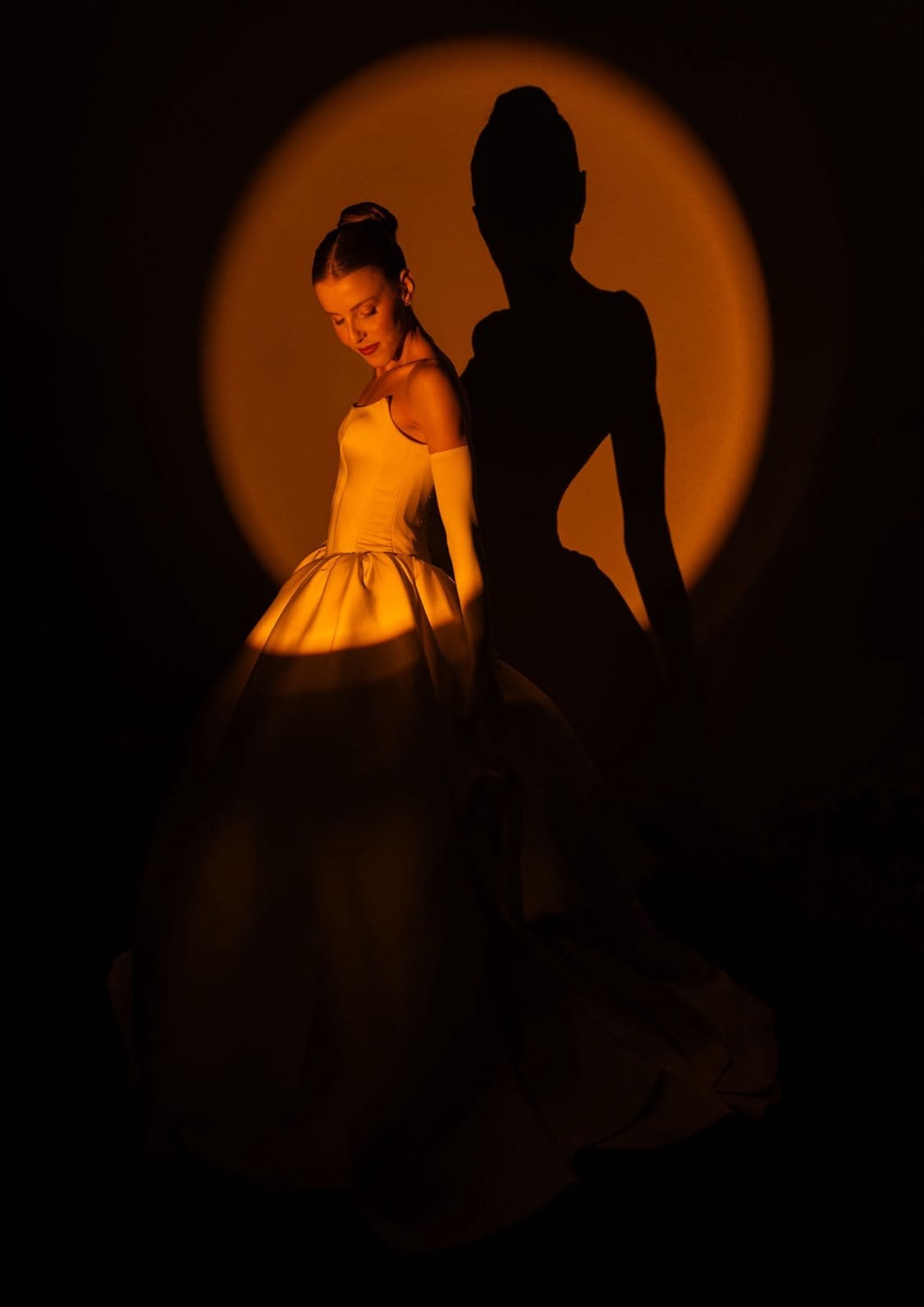 Bride in an amber spotlight beside her own shadow