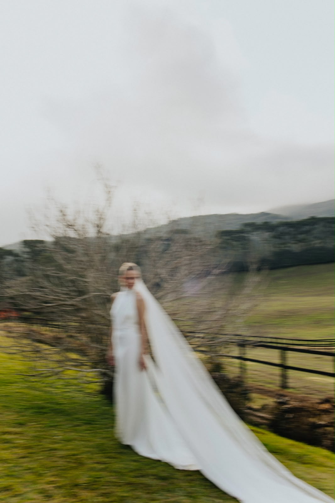 Bride with a long veil on a misty hillside